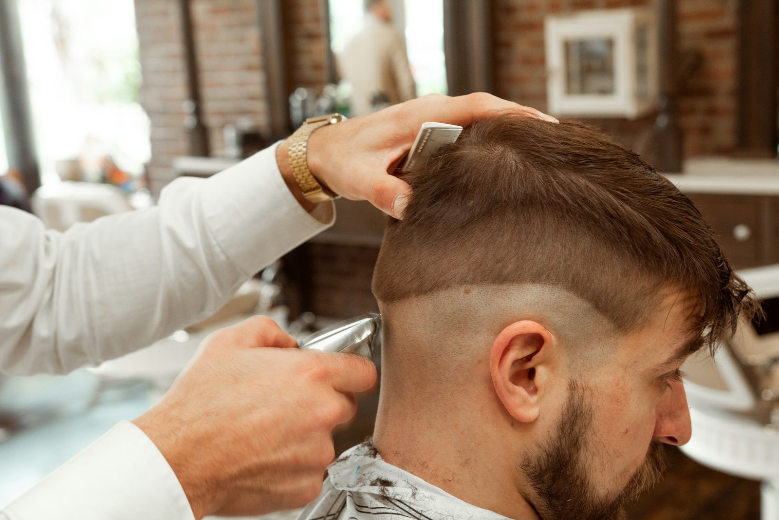 Kapster sedang memotong rambut pelanggan pria di kursi barbershop