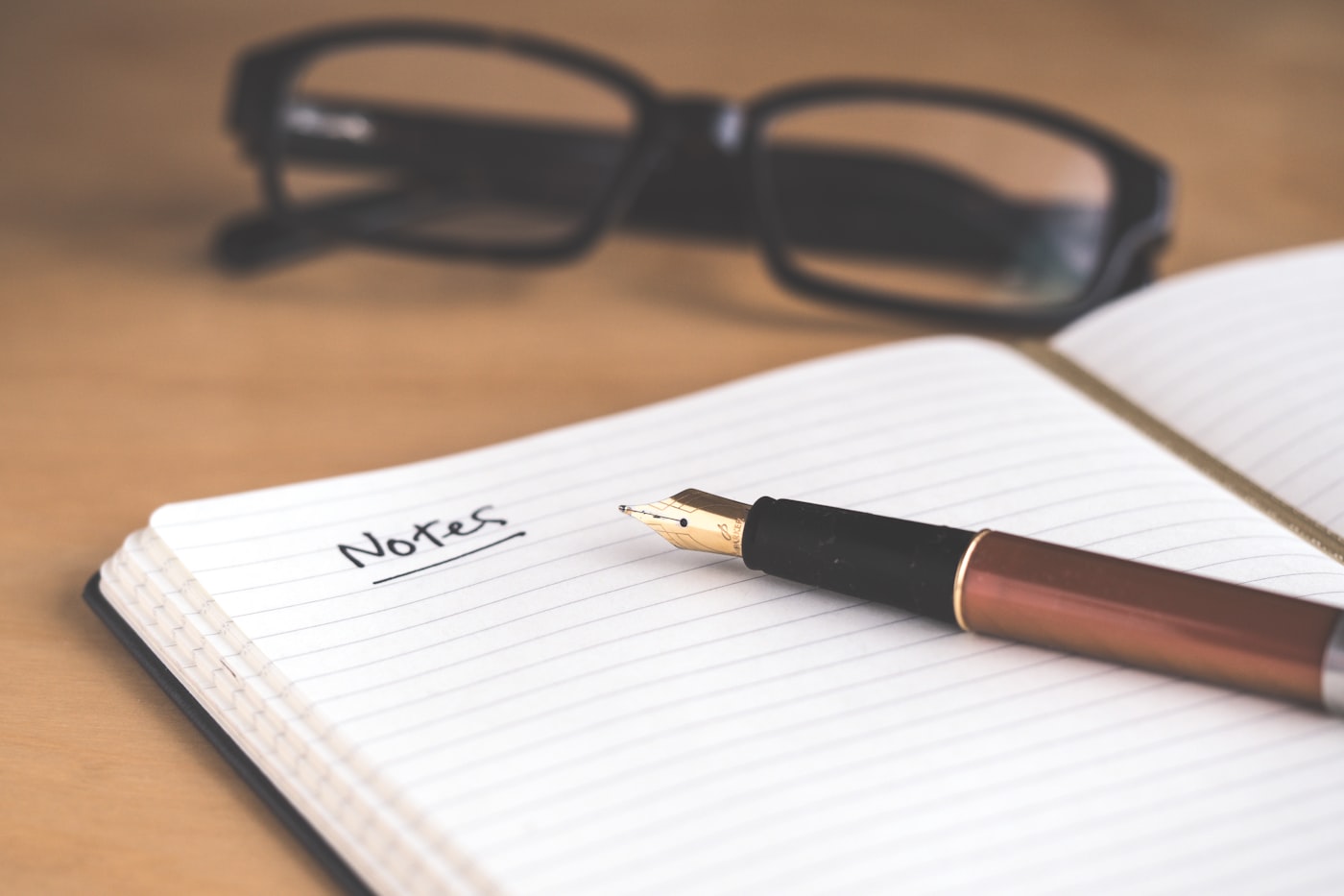 Buku catatan dengan pena dan kacamata