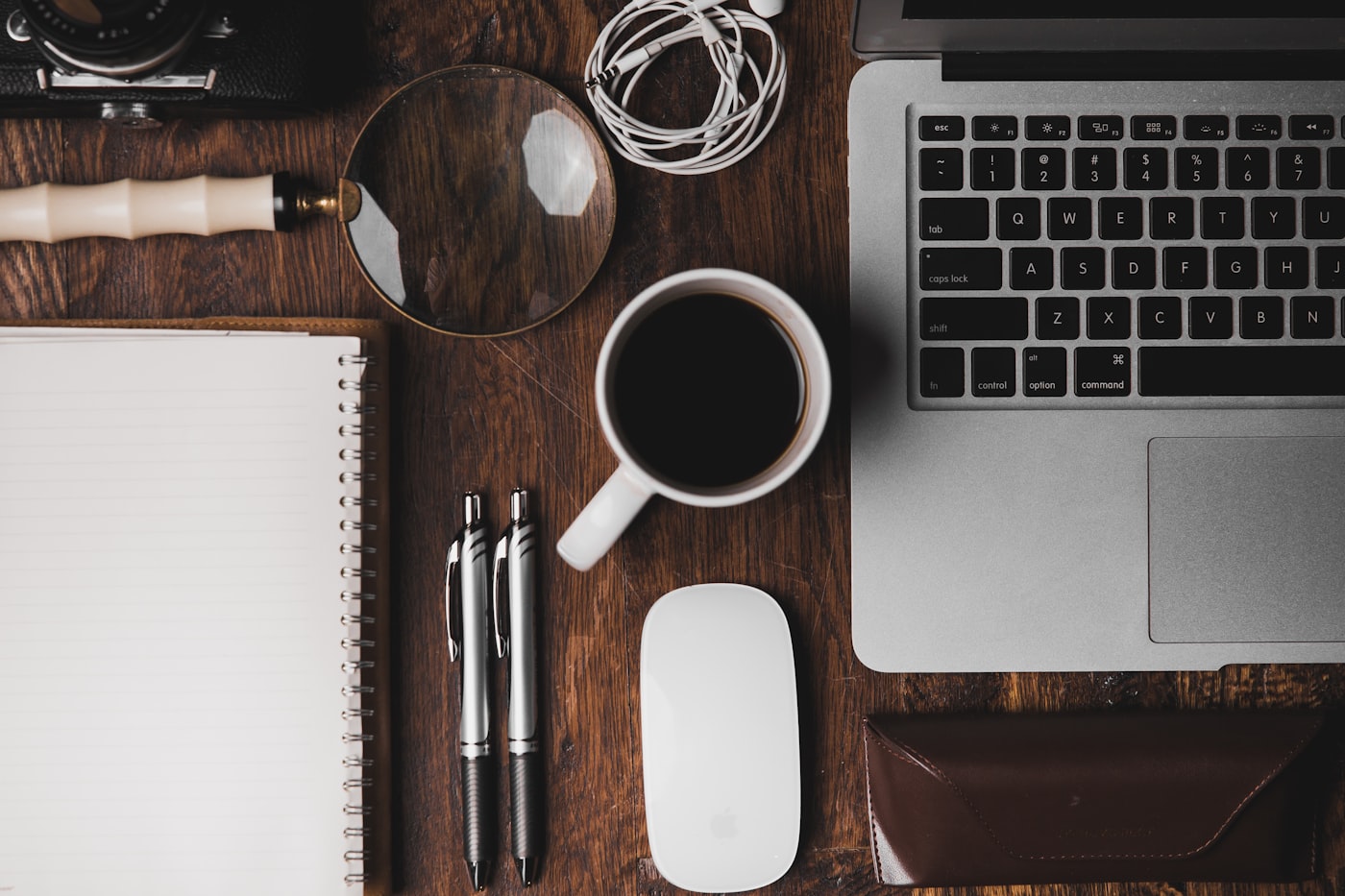 Meja kerja dengan buku catatan, kopi, dan laptop