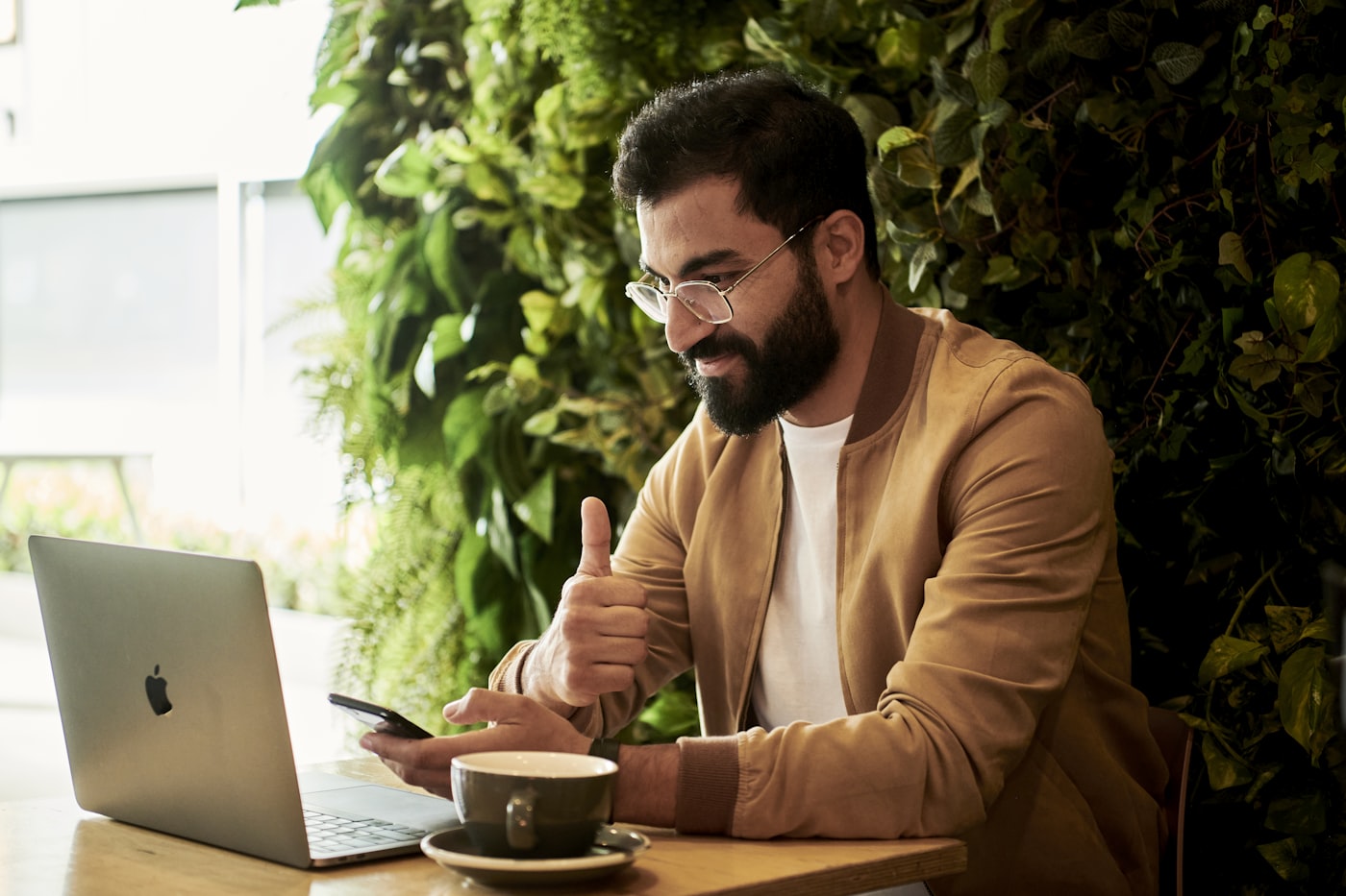 Pria bekerja dengan laptop di kafe berhias tanaman