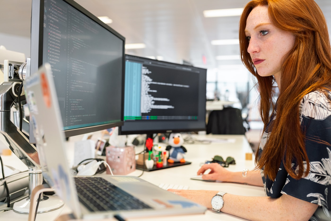 Programmer wanita bekerja di depan dua monitor